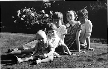 Siblings sitting together on the grass in a vintage black-and-white family photo